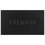 Plush Erewhon Beach Towel in black folded beside its water-resistant travel bag, showcasing the minimalist 3D Jacquard logo in black, apricot, and forest green.