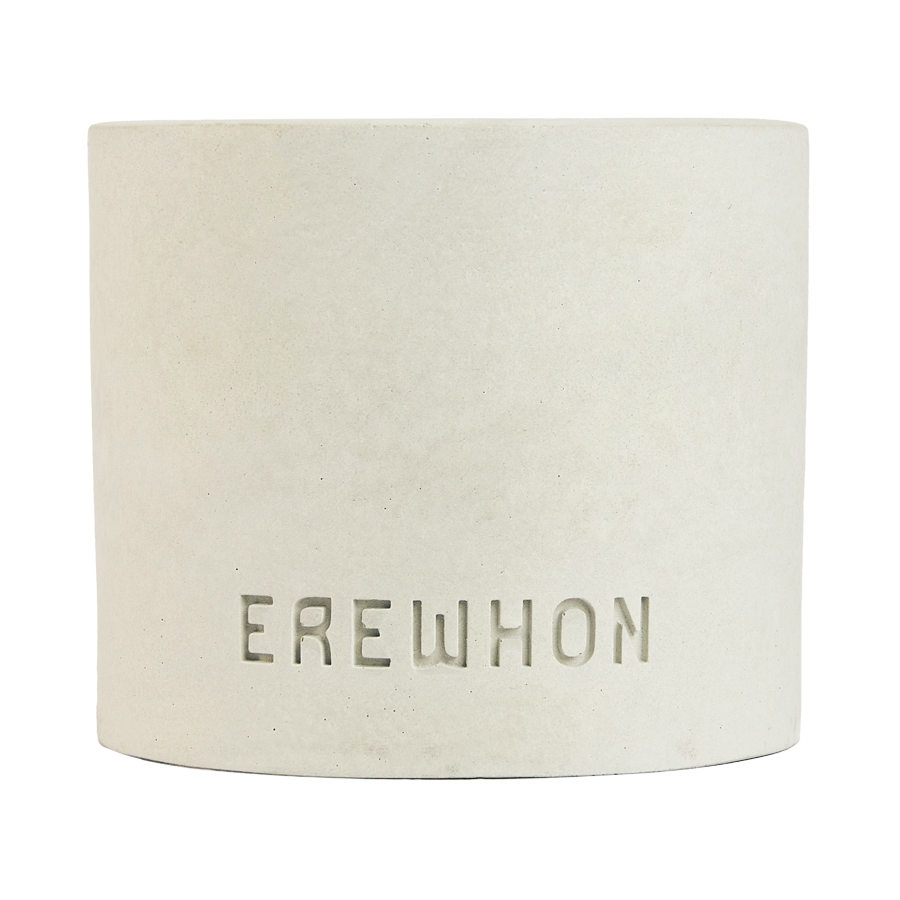A handcrafted Erewhon candle made of concrete, with a white finish and the brand name embossed on the front.
