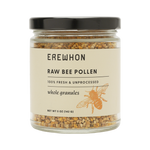 A jar of Erewhon Raw Bee Pollen with whole granules visible through the transparent glass. The label displays the brand name and product details.