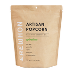 A package of Erewhon Artisanal Organic Spirulina Popcorn, with a label indicating that it is made with coconut oil and spirulina, and free from gluten, GMOs, dairy, and preservatives.