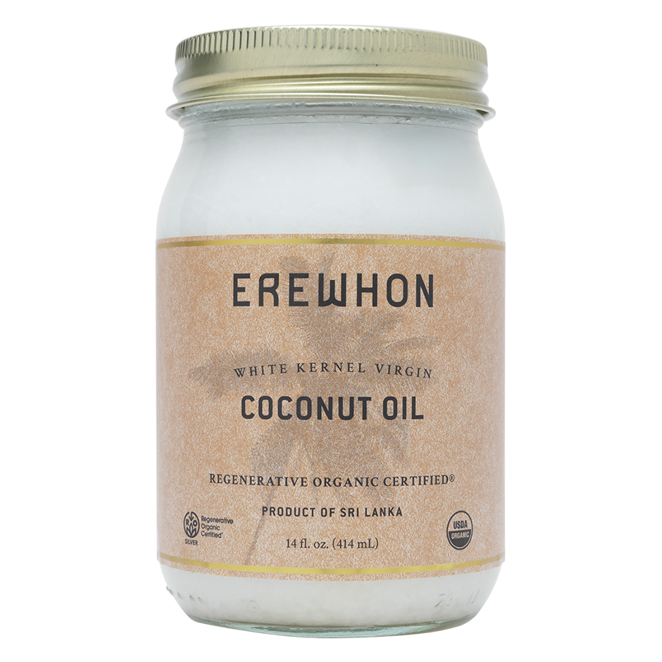 A glass jar of Erewhon White Kernel Virgin Coconut Oil with a label indicating that it is Regenerative Organic Certified, with a net content of 14 fl oz (414 ml).