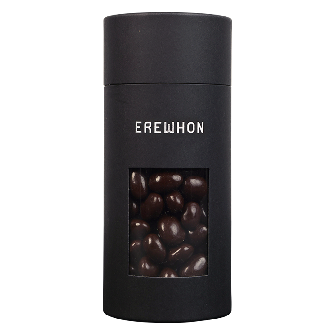 A sleek black canister of Erewhon dark chocolate covered almonds with a window showing the almonds inside.
