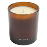 Candle in a brown glass container with 'Erewhon' branding on a white background