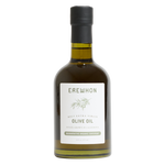 A bottle of Erewhon Roasted Extra Virgin Olive Oil on a solid white background. The bottle is made of dark glass showing the golden-olive oil inside, has a black screw cap, and a white label with green text and a small olive branch illustration.