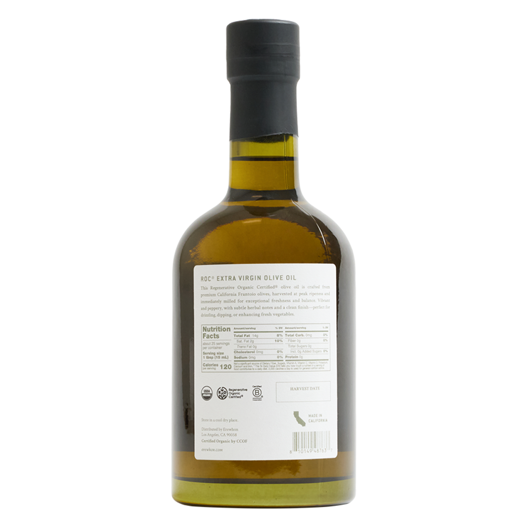 The back of a glass bottle of Erewhon ROC Organic Extra Virgin Olive Oil, showing the white product label and a black cap, on a solid white background.