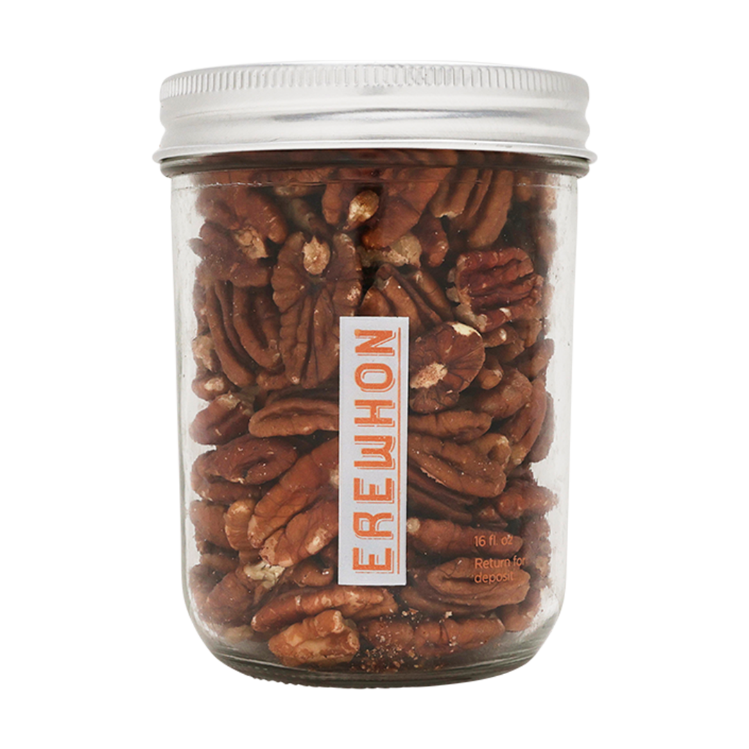 A clear glass jar filled with raw pecans, with a white label that has the brand name 'EREWHON' written on it.